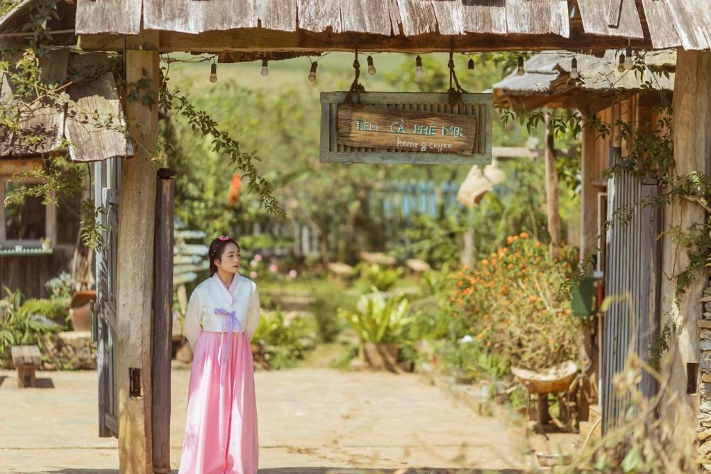 木州的住宿－Tiệm Cà Phê Mer Homestay & Coffee Mộc Châu，站在花园中的身着粉红色衣服的女人