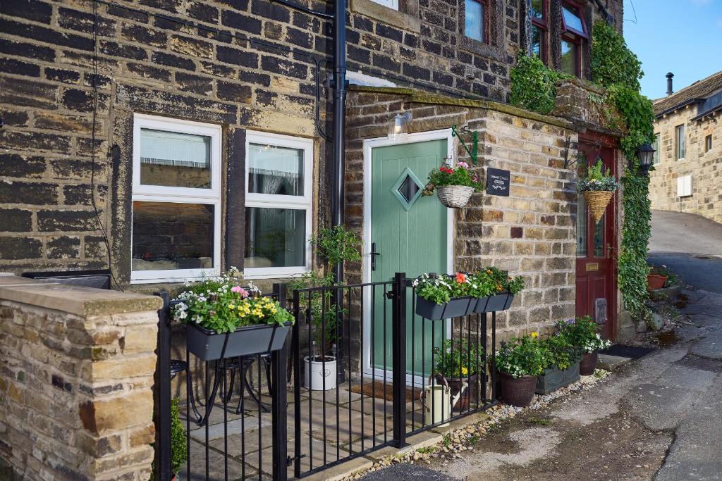 a brick house with a green door and potted plants at Chimney Cottage in Holmfirth