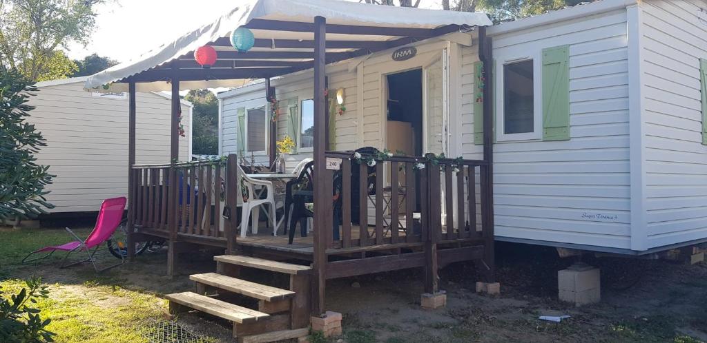 a tiny house with a porch and a deck at Splendide mobil-home in Narbonne