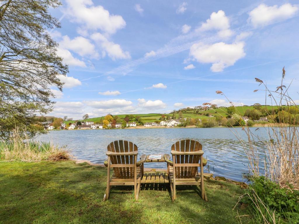 two chairs and a table next to a lake at Clerk Beck Cottage in Ulverston