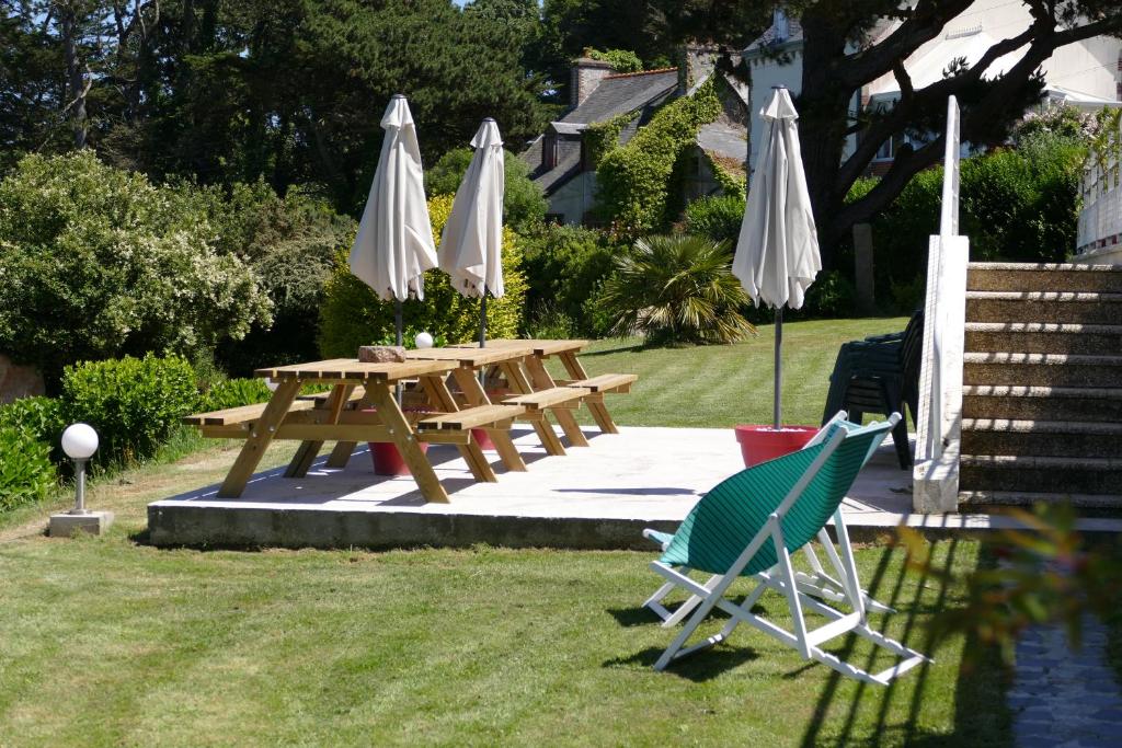 a picnic table and two chairs and umbrellas at Kerbugalic Grand gîte, Magnifique vue mer in Trévou-Tréguignec