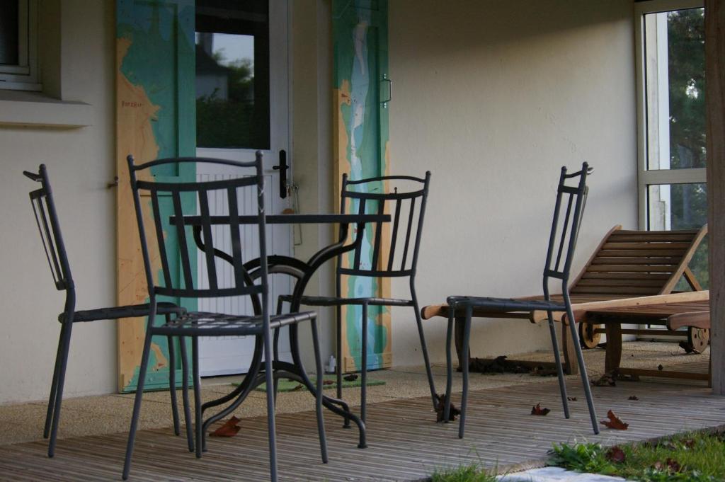 three chairs and a table on a porch at Kerbugalic Grand gîte, Magnifique vue mer in Trévou-Tréguignec