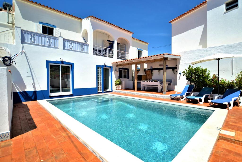 une villa avec une piscine en face d'une maison dans l'établissement Vila Arvela, à Albufeira