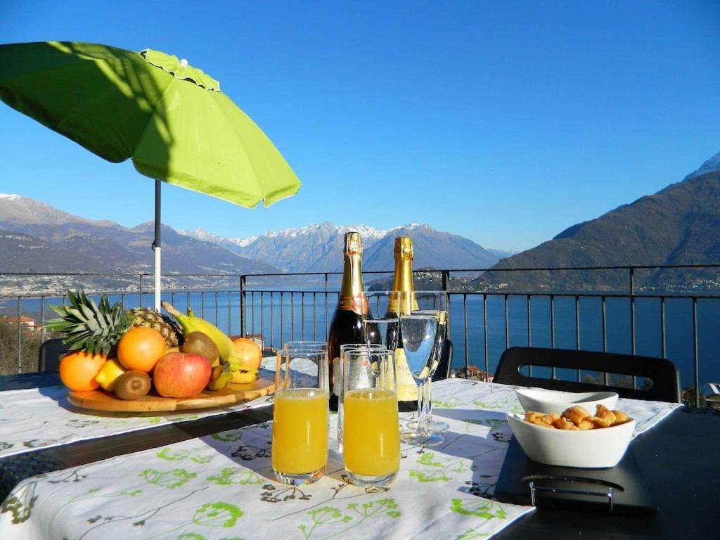 een tafel met twee flessen champagne en een fruitschaal bij Balcony on Lake Pianello in Pianello Del Lario