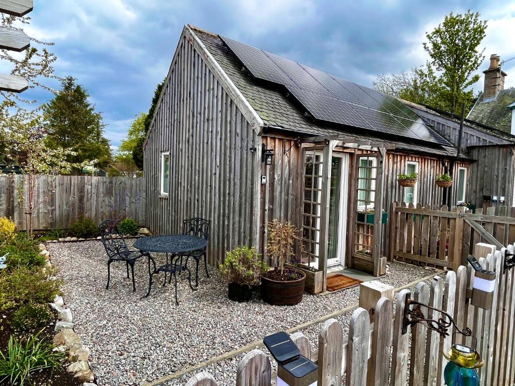 a small shed with a table and a fence at Courtyard Bothy in Grantown on Spey