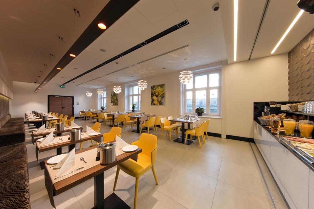 a dining room with tables and yellow chairs at Boutique Hotel Victoria Budapest in Budapest