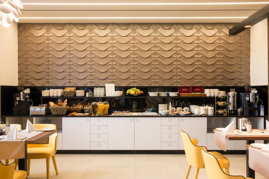 a restaurant with white counters and yellow chairs at Boutique Hotel Victoria Budapest in Budapest