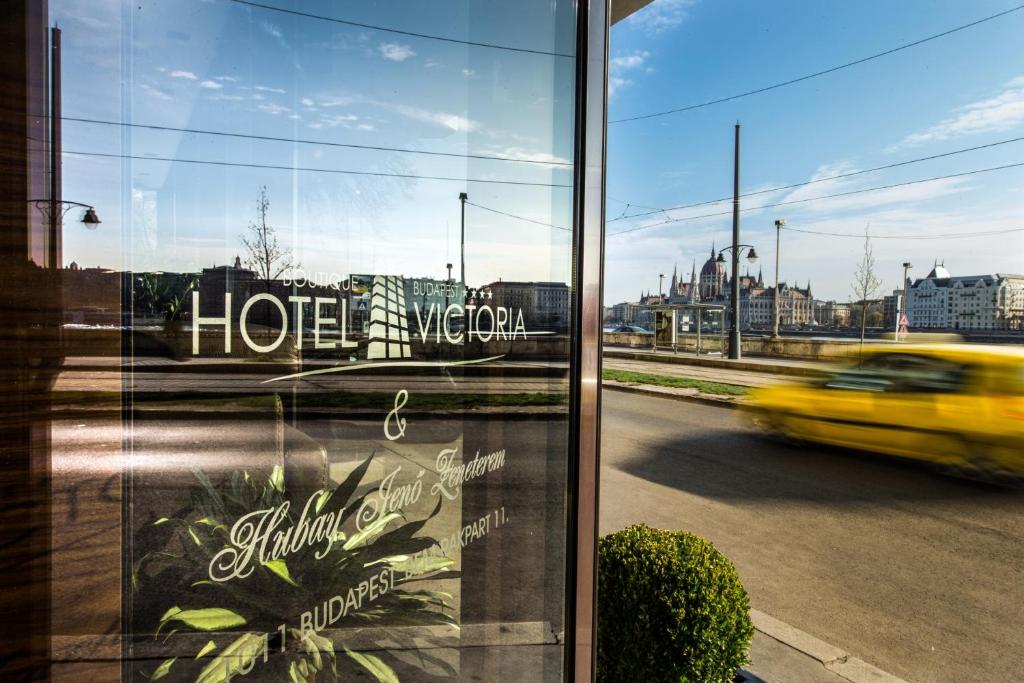 a reflection of a yellow car driving down a street at Boutique Hotel Victoria Budapest in Budapest
