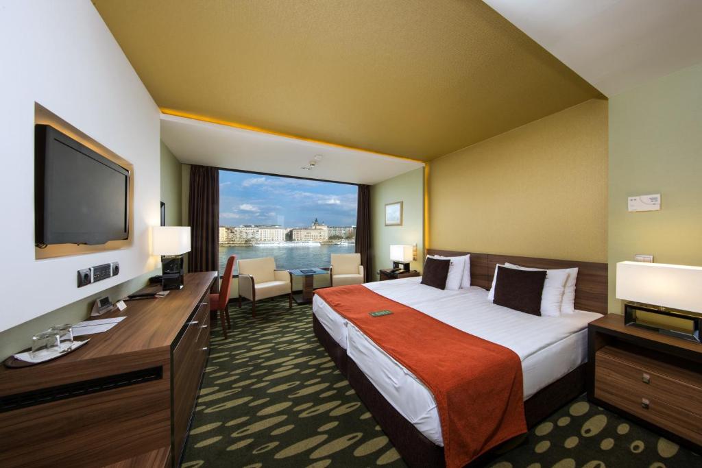 a hotel room with a large bed and a large window at Boutique Hotel Victoria Budapest in Budapest