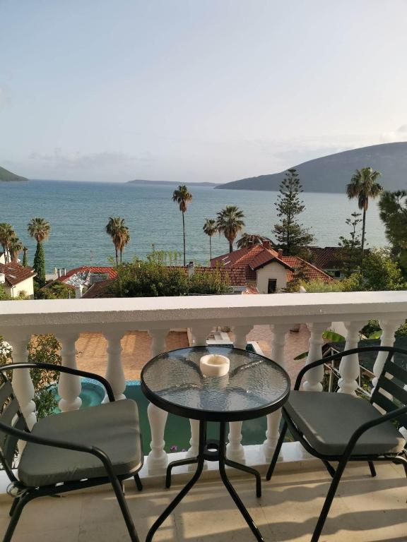 a table and chairs on a balcony with a view of the ocean at Petrovic house in Herceg-Novi