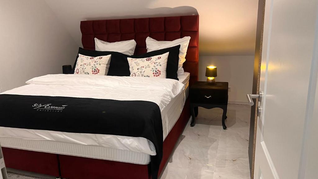 a bedroom with a large bed with a red headboard at RelaxDays-Apartments 2 GARTEN und POOL- Mitbenutzung, kostenloser Parkplatz, kontaktloser CheckIn, WiFi mit SmartTV in Gütersloh