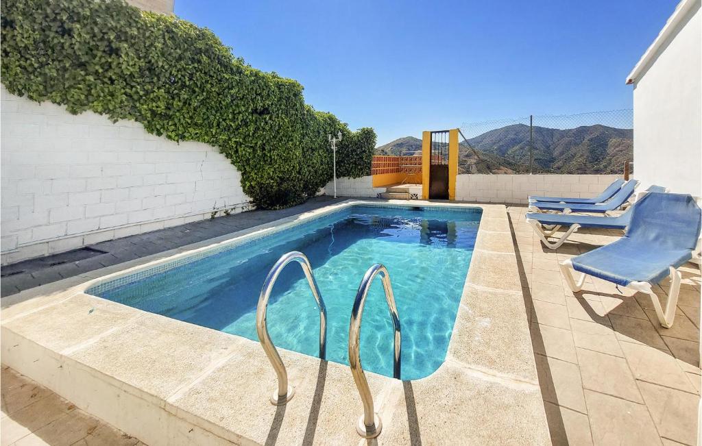una piscina con 2 sillas junto a un edificio en 4 Bedroom Lovely Home In Almchar en Almáchar