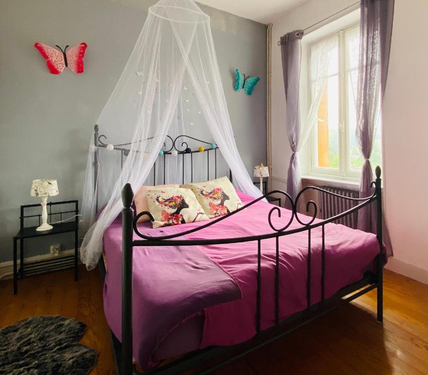 ein Schlafzimmer mit einem Bett mit Baldachin und rosa Bettwäsche in der Unterkunft Chambre ZEN proche de Bagnoles de lOrne in La Ferté-Macé
