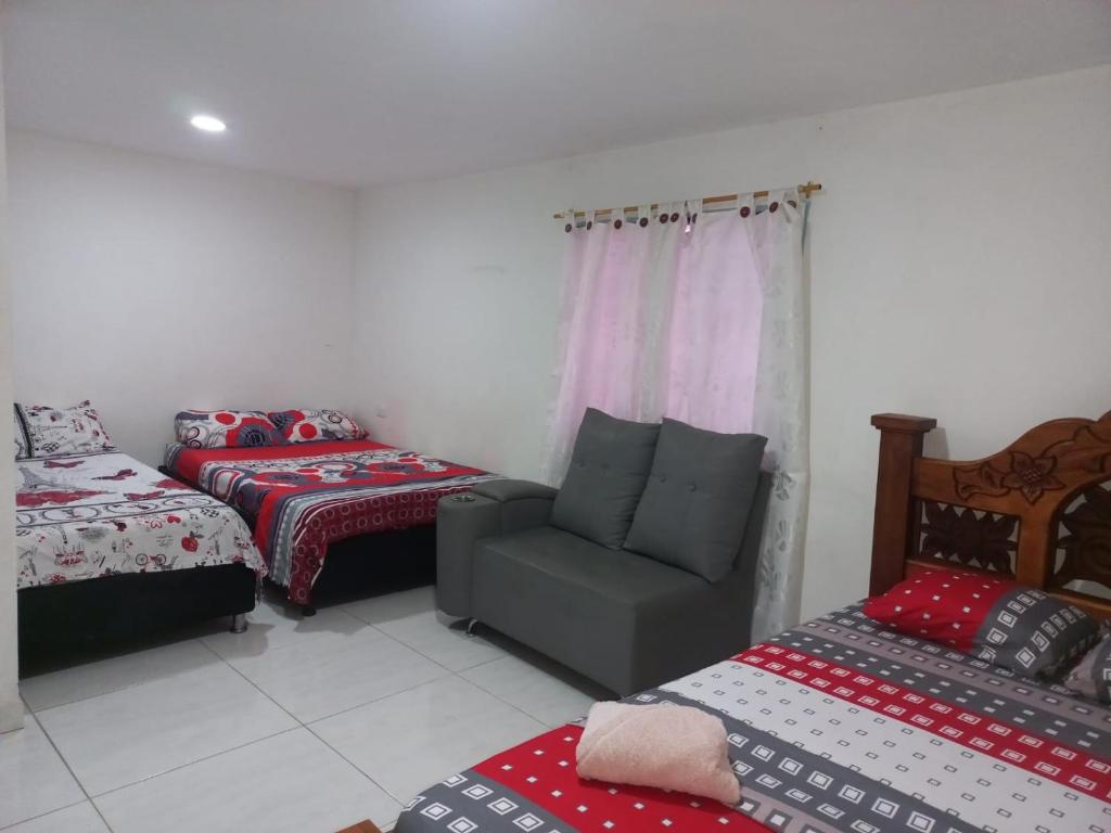 een kamer met 2 bedden en een bank en een stoel bij Hotel 7 in Cúcuta