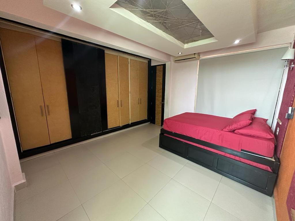um quarto com uma cama vermelha num quarto em Isla vancouber em Acapulco