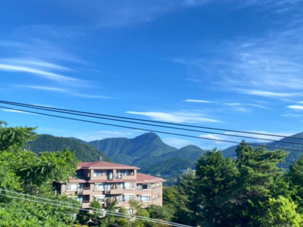a building on a hill with mountains in the background at Gora Onsen Kinkaku 金閣莊 預約制免費個人湯屋 Private onsen free by Reservation in Hakone