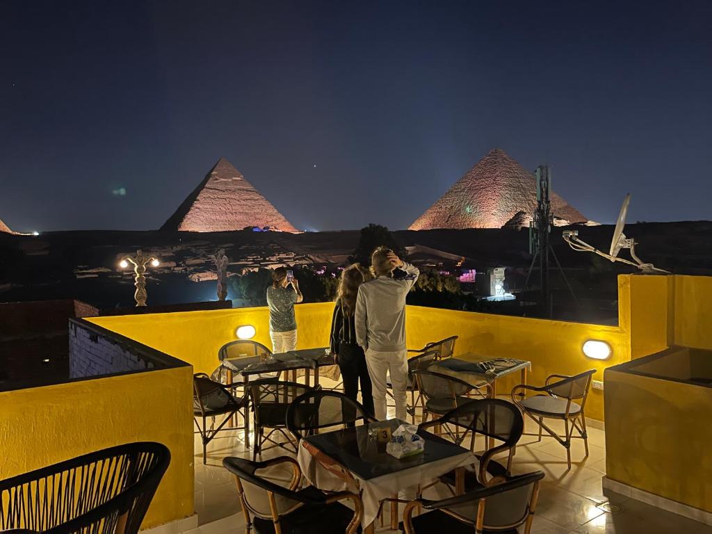 un par de personas de pie en un balcón con pirámides en Pyramids Plateau View, en El Cairo