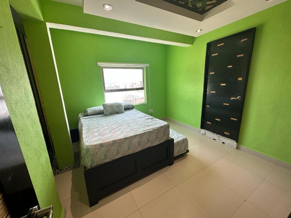 a green bedroom with a bed and a window at Isla Cozumel in Acapulco