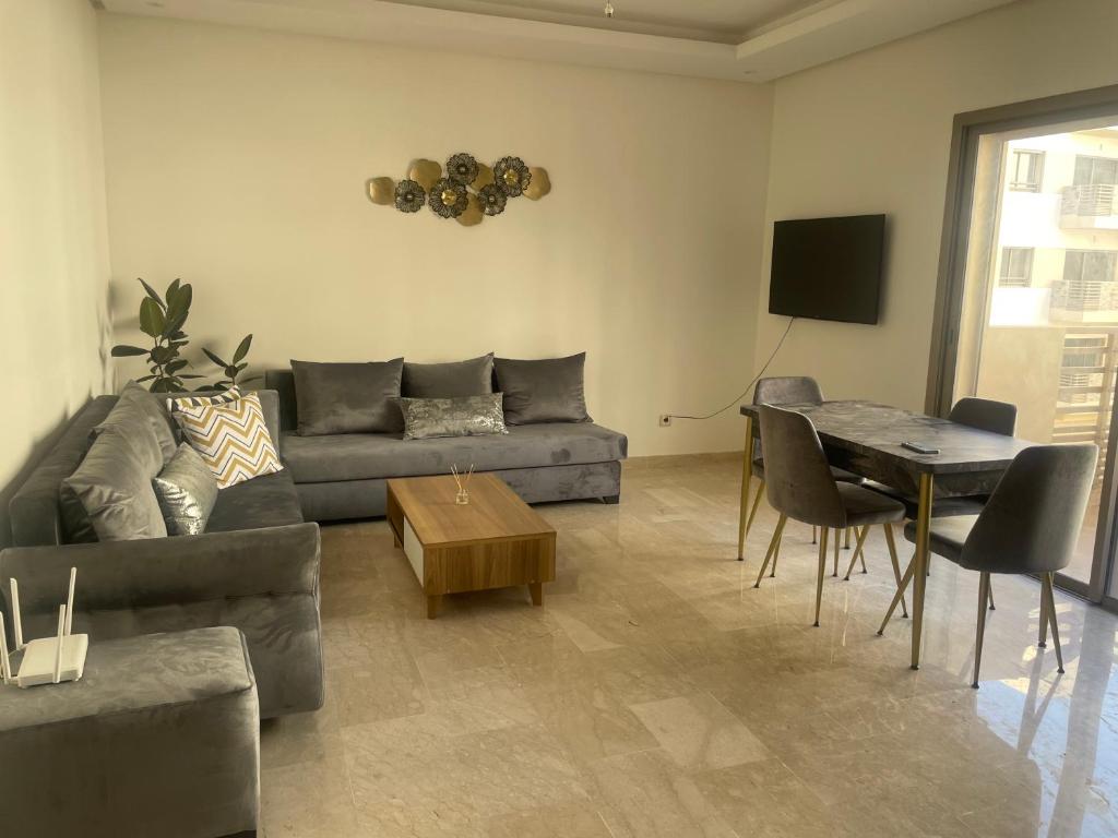 uma sala de estar com um sofá e uma mesa em Taj appartement/ aeroport M 5 em Nouaceur
