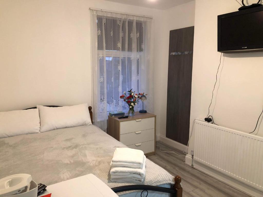 1 dormitorio con cama, ventana y TV en En Suite Double Room en Londres
