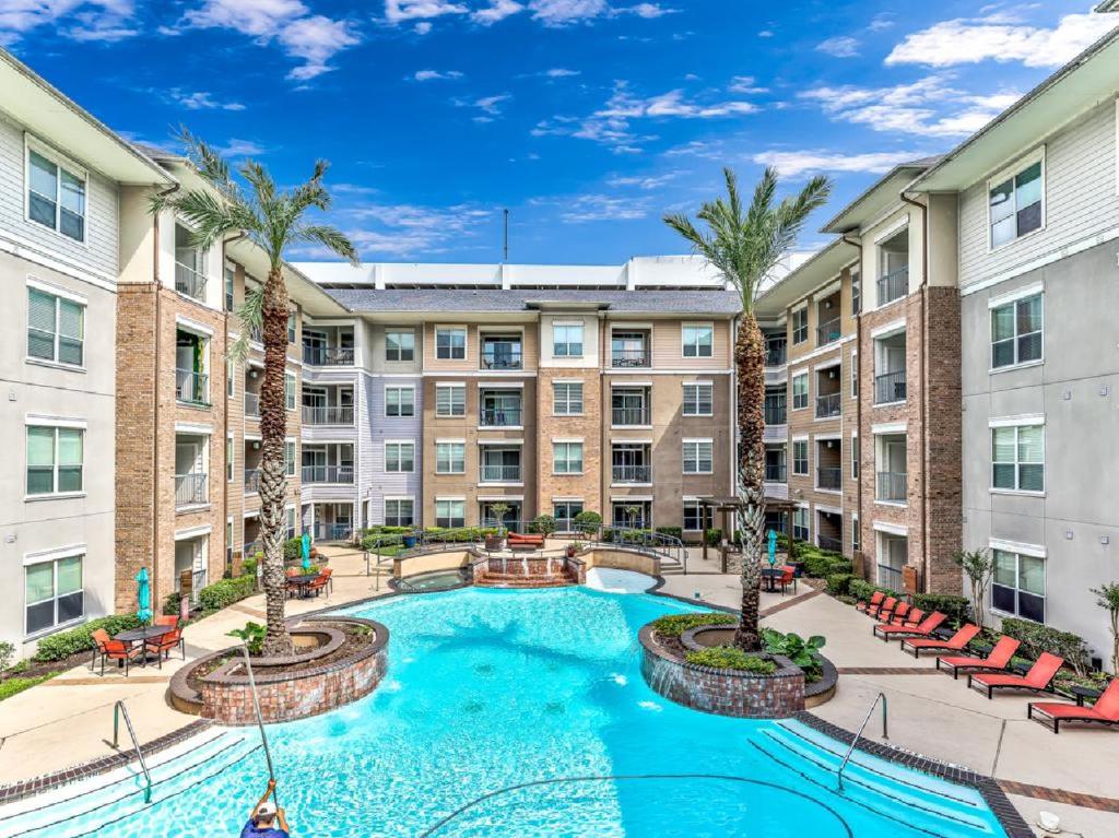 an apartment courtyard with a pool and palm trees at Elegant 2BR Ideal for Long Term Stay in Houston