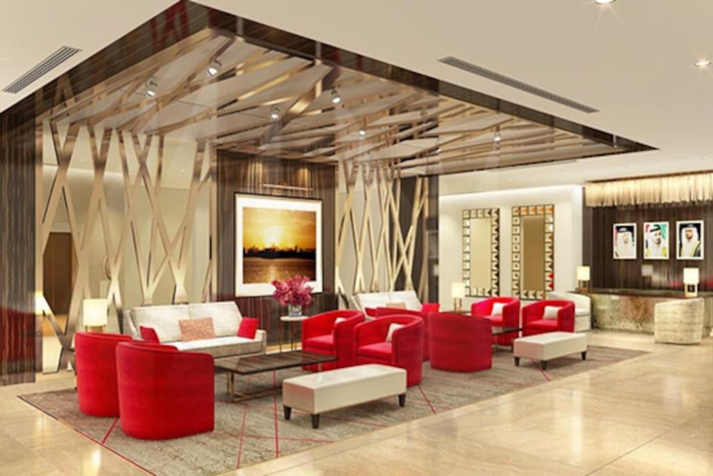 a lobby with red chairs and couches at Brand New Apartment with Gym and Pool in Dubai