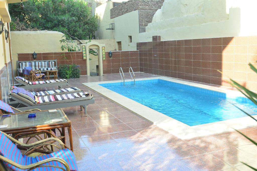 a swimming pool with two chairs next to a building at Villa Belzoni in Luxor