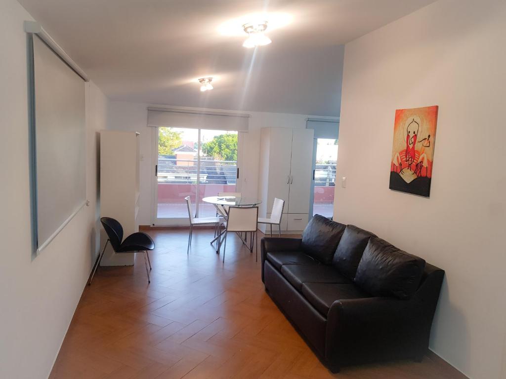 a living room with a leather couch and a table at Torre Libertad Departamentos Amoblados in San Isidro