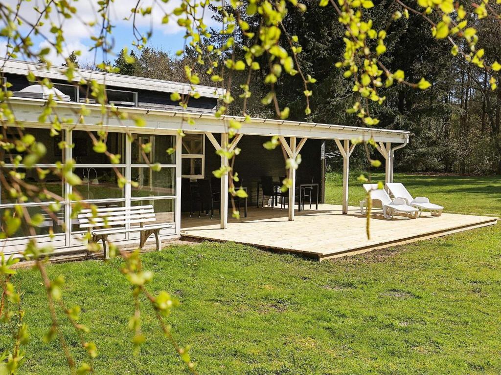 une terrasse en bois avec deux chaises et une maison dans l'établissement 8 person holiday home in Hals, à Øster Melholt