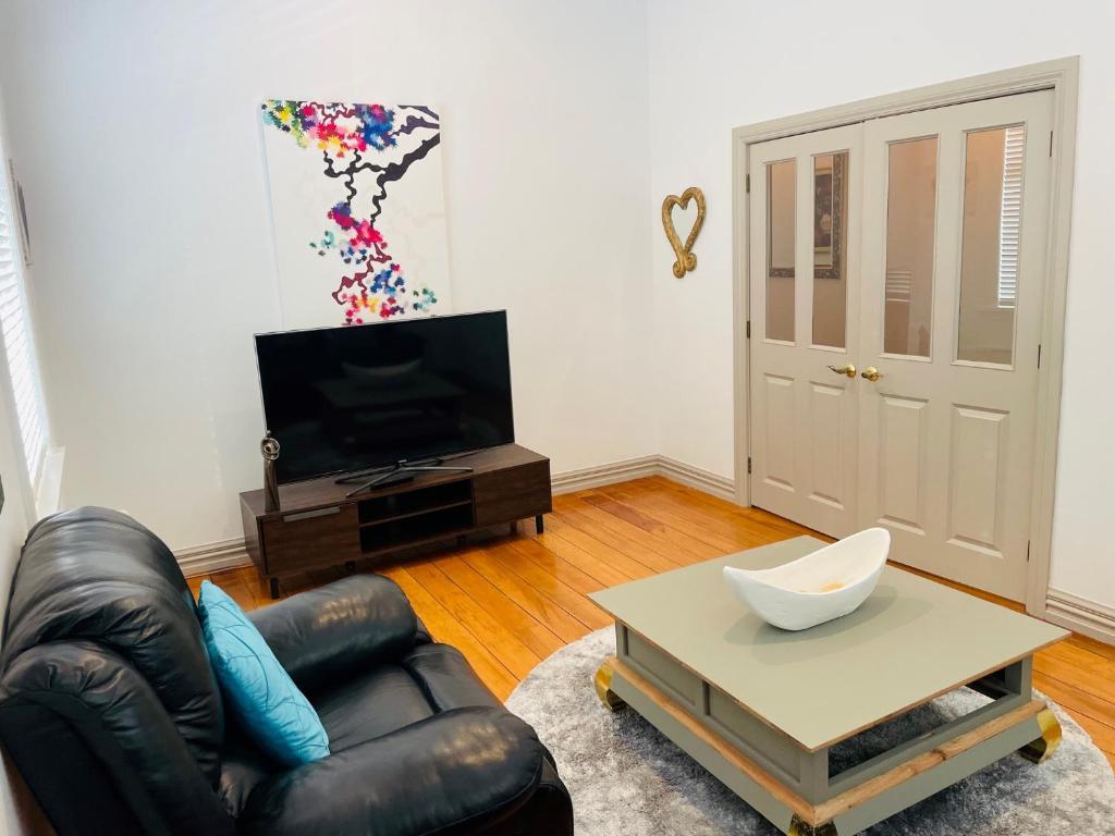 a living room with a black leather couch and a table at Central Hut Villa in Lower Hutt