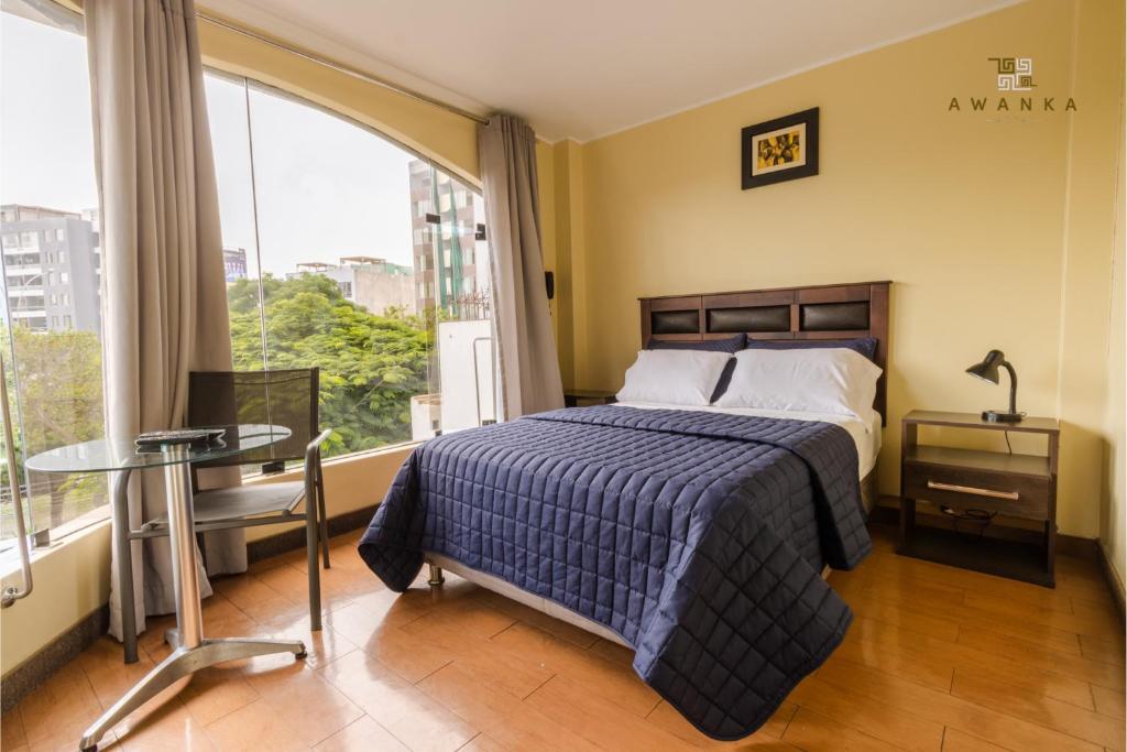 1 dormitorio con cama, mesa y ventana en San Miguel Awanka Hotel en Lima