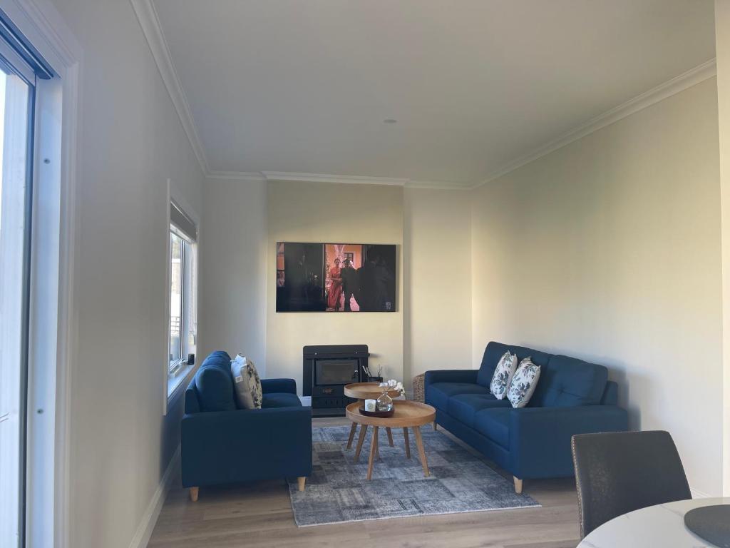 una sala de estar con 2 sofás azules y una mesa. en 2bdrms, space for caravan and close to "The Spirit", en Ambleside