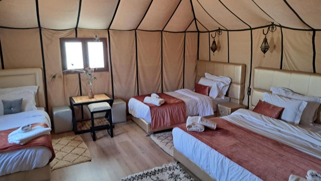 a room with three beds in a tent at Sahara Sky Luxury Camp in Merzouga