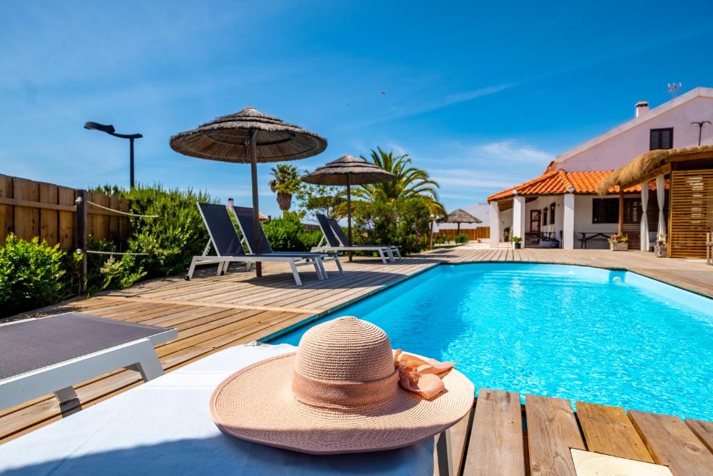 a hat sitting on a deck next to a swimming pool at Flow Rooms in Comporta