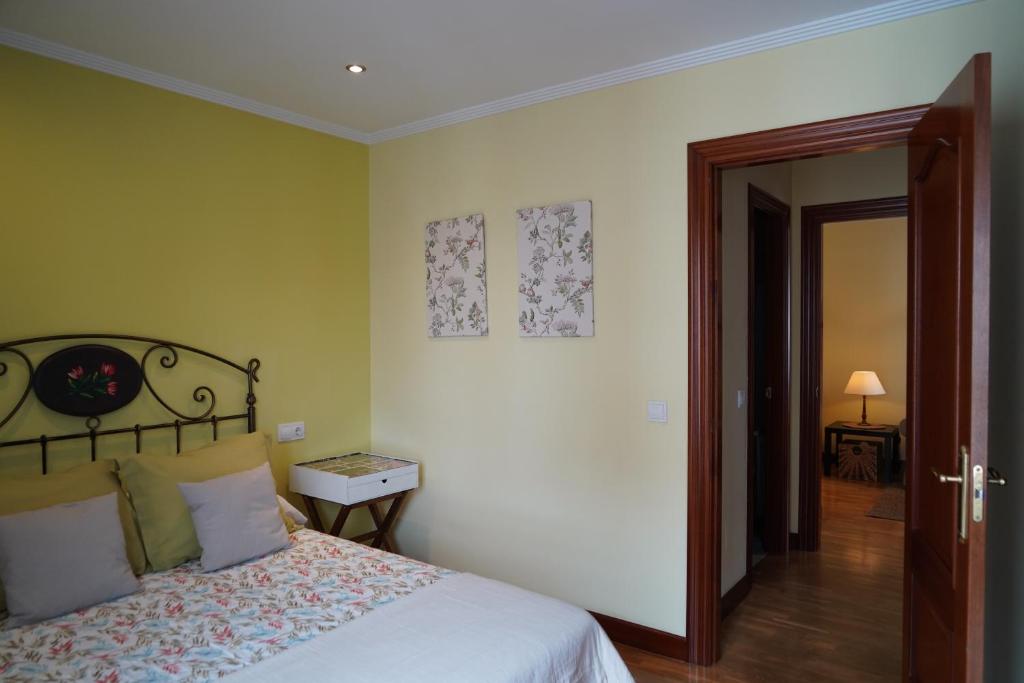 ein Schlafzimmer mit einem Bett und einer Tür zu einem Flur in der Unterkunft ALMAR, Apartamento en Luanco. in Luanco