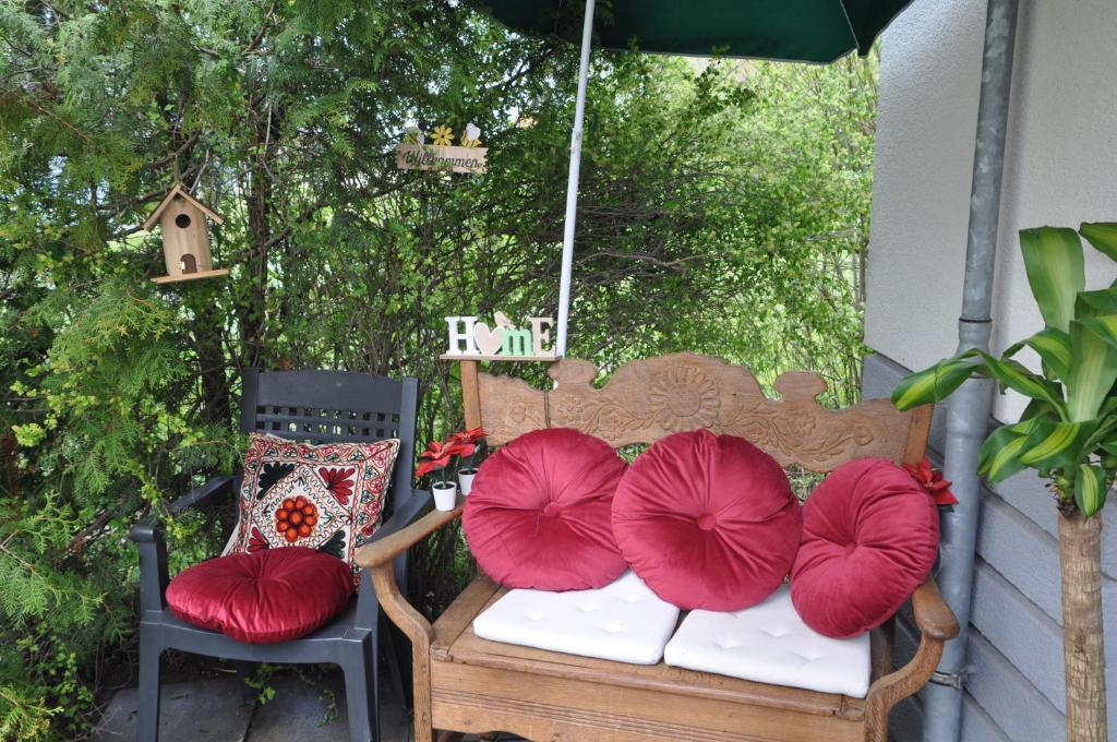 a bench with red pillows on it next to two chairs at TerraceOasisBerlinAirport in Schönefeld