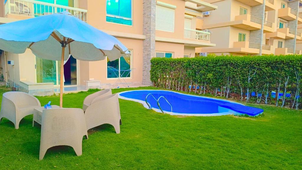 a table and chairs with an umbrella next to a swimming pool at Marina Delta in Al Ḩammād