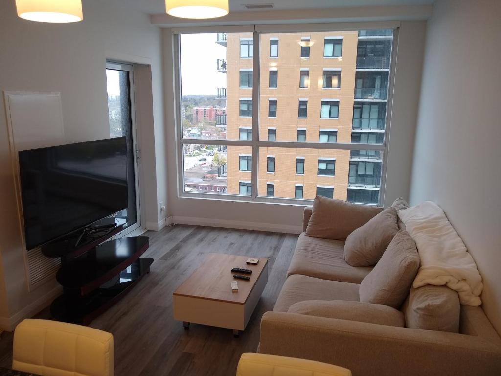 a living room with a couch and a large window at Comfy Condo Near Downtown in Kitchener