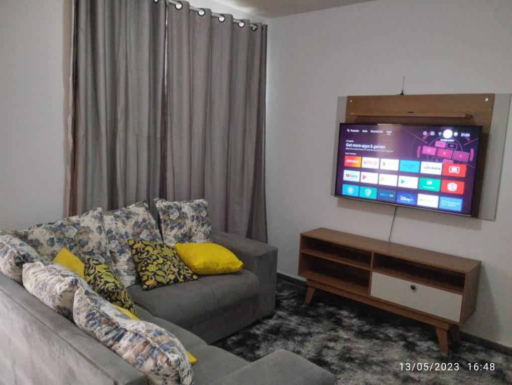 ein Wohnzimmer mit einem Sofa und einem Flachbild-TV in der Unterkunft Andres home casa J in Governador Valadares