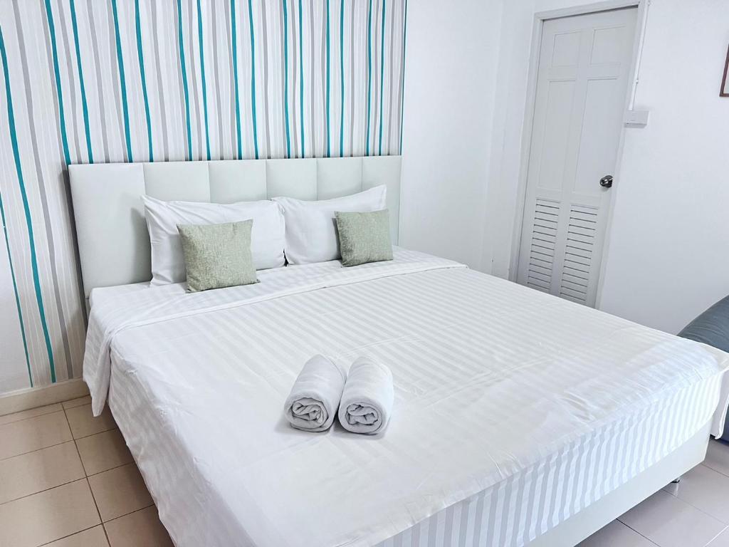 Una cama blanca con dos pares de zapatos. en Malizon Hotel and Residences en Nonthaburi