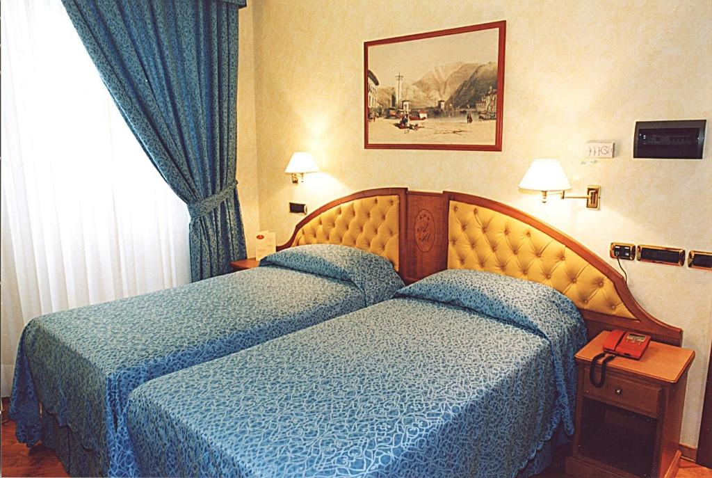 a hotel room with two beds and a window at Hotel Antico Masetto in Lamporecchio