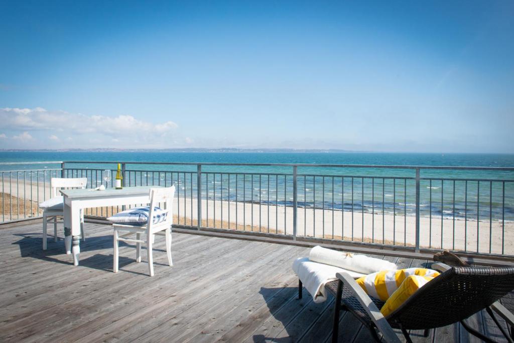 una terraza con mesa y sillas y la playa en Lodge am Meer, en Glücksburg