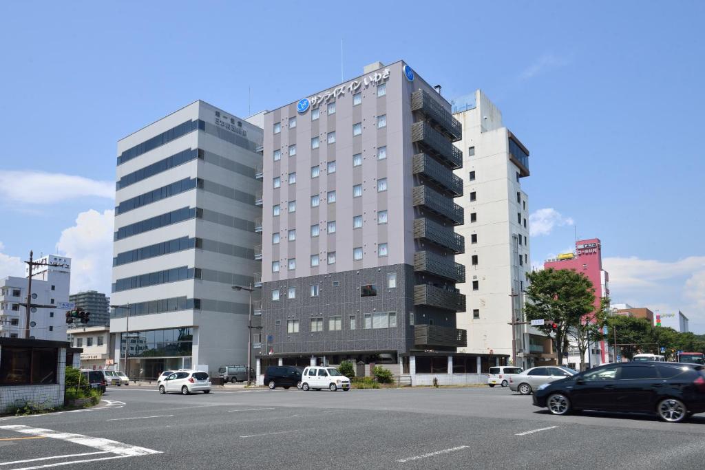 un gran edificio con coches estacionados en un estacionamiento en Sunrise Inn Iwaki, en Iwaki
