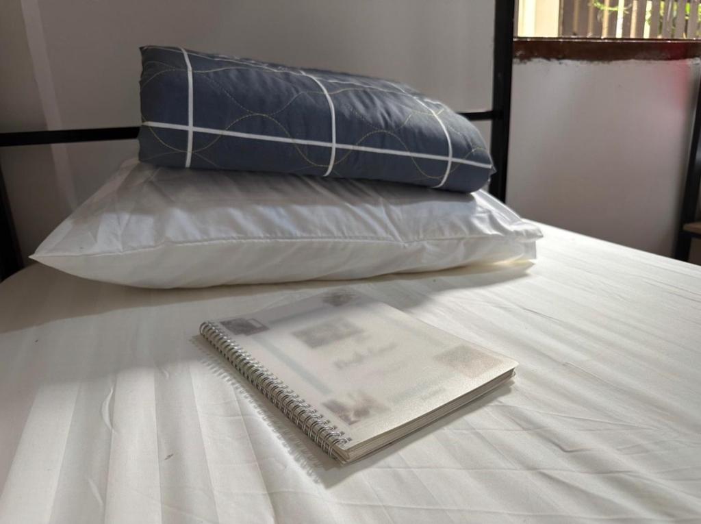 un cuaderno sentado en la parte superior de una cama con dos almohadas en Aurora Backpackers Hostel, en Luang Prabang