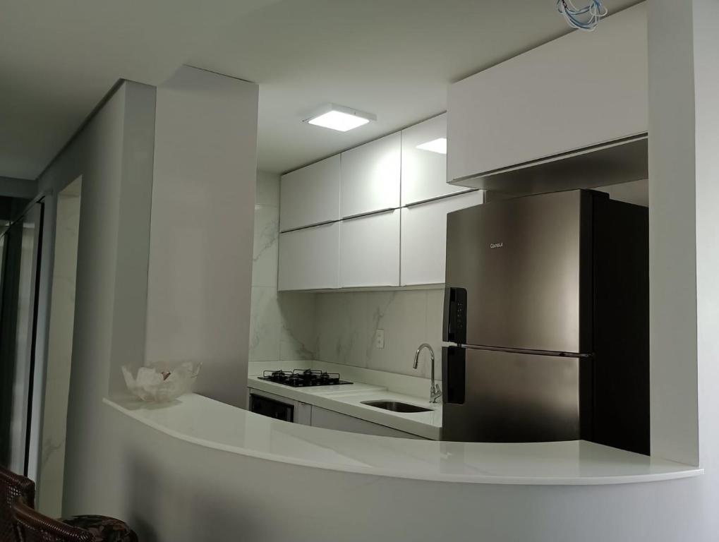 a kitchen with white cabinets and a stainless steel refrigerator at Apt na Torre - Recife in Recife