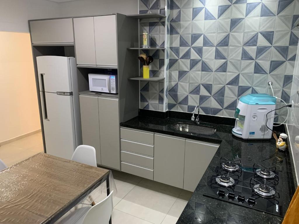 a small kitchen with a black counter top at Apto frente praia Gonzaguinha in São Vicente