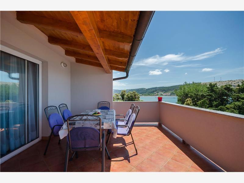eine Terrasse mit einem Tisch und Stühlen auf dem Balkon in der Unterkunft Apartmani 'Mirijana Gabrić' A3 in Lopar