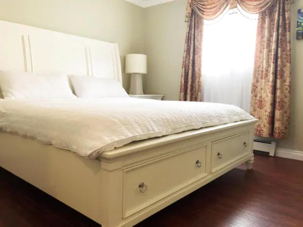 a bedroom with a large white bed with a window at Jane's private rooms with shared washroom in Surrey