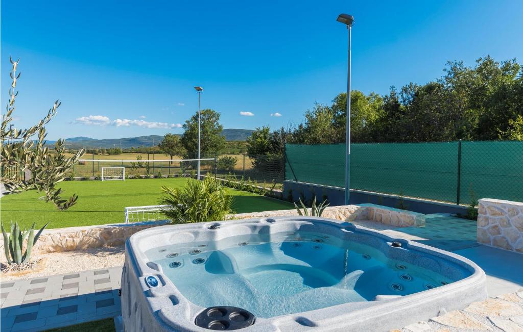 a hot tub in a yard with a tennis court at Stunning Home In Siveric With 5 Bedrooms, Jacuzzi And Outdoor Swimming Pool in Siverić