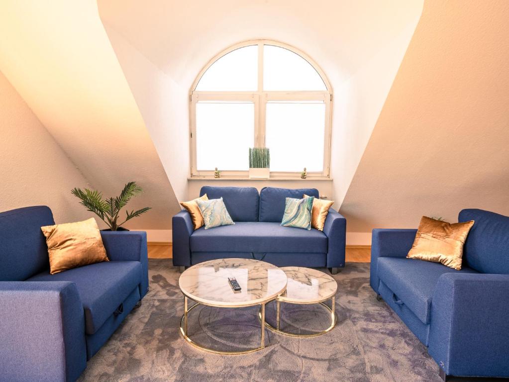 ein Wohnzimmer mit 2 blauen Sofas und einem Tisch in der Unterkunft Penthouse-Suite near University in Gießen